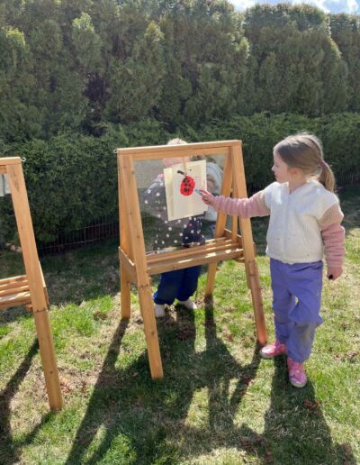 Montessori young girl painting outside